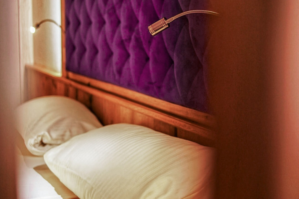 Close-up view of the pillows and purple headboard of the kingsize bed